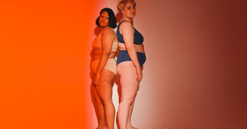 Two plus-size models are showcasing innerwear products in a photoshoot with a gradient background.