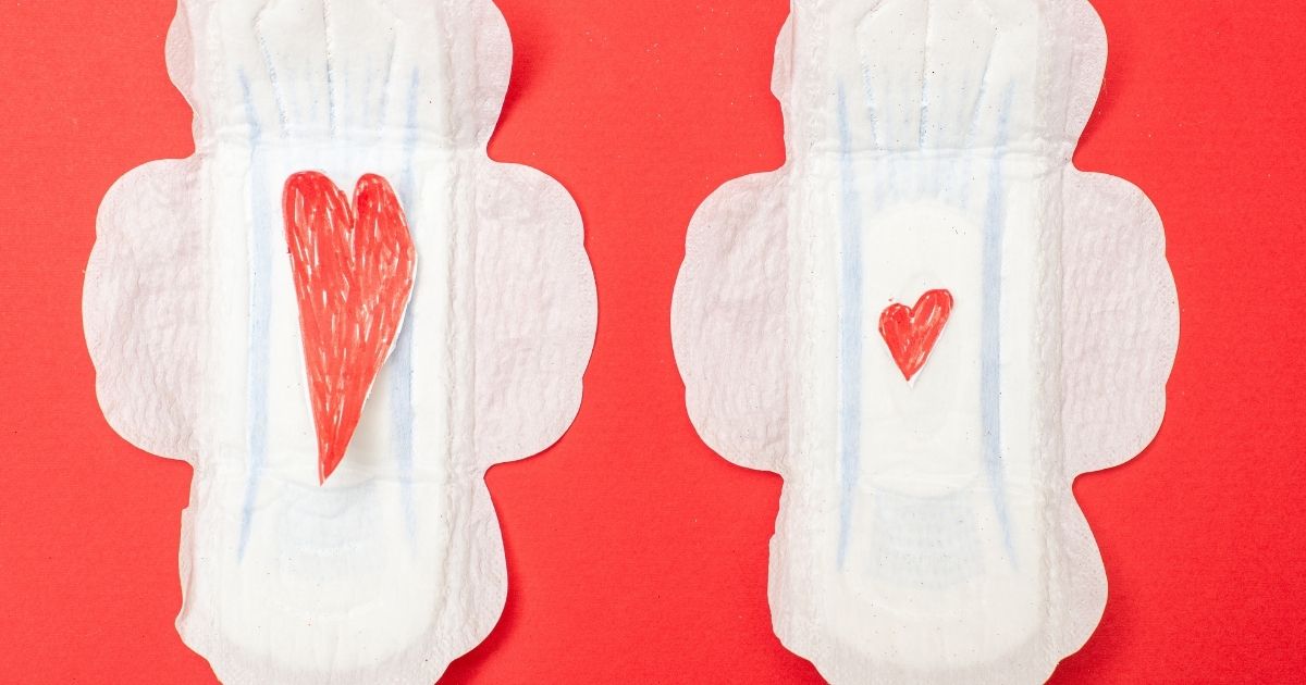 Pair Of White Sanitary Pads with Red Petals on Pink Surface