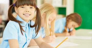Image of a schoolgirl smiling while sitting in a classroom at school.