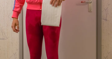Wet-legged woman holds white adult incontinence diaper, representing urinary incontinence and medical challenges