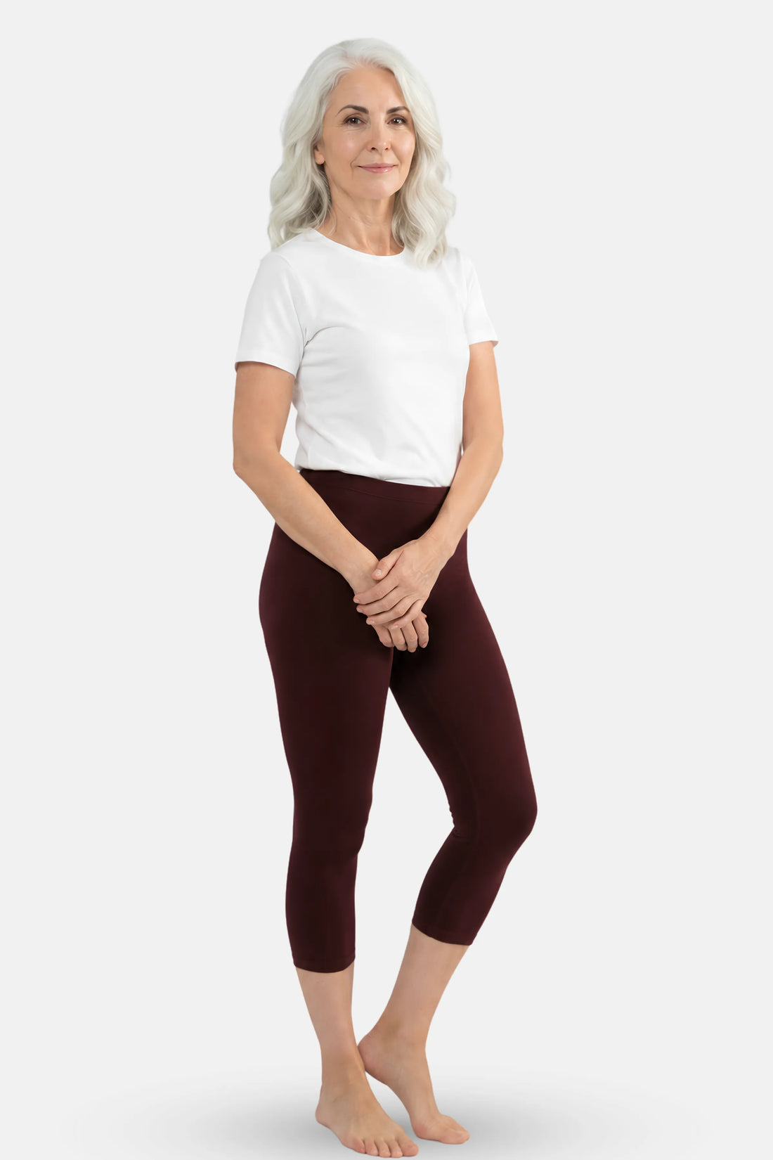 An elder woman wearing a white t-shirt and brown capri leggings.