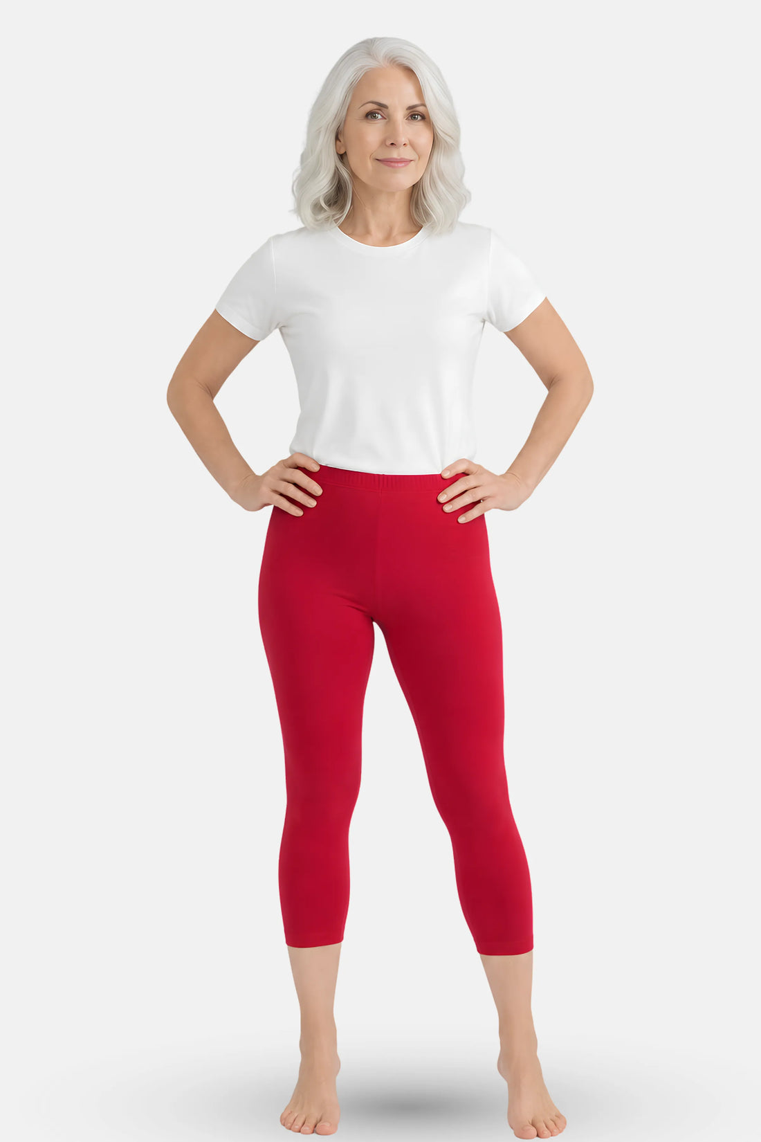 A woman wearing a white short t-shirt and dark pink high-waisted capri leggings.