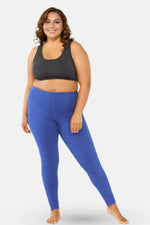 Woman wearing a black sports bra and blue leggings on a white background