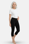 An elder woman wearing a white t-shirt and black high-waisted capri leggings.