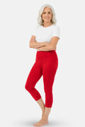 A elder woman wearing bright red high-waisted capri leggings and a white top.