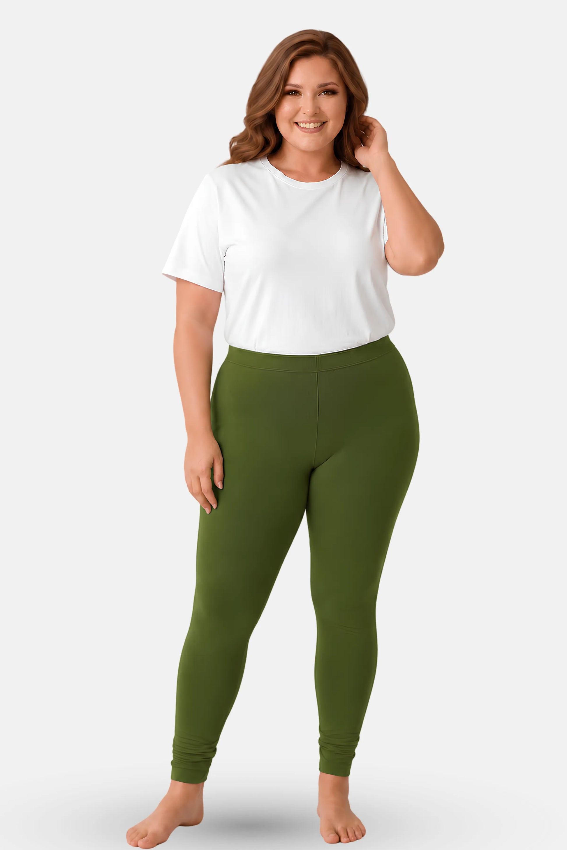 A woman modeling green churidar leggings with a white short t-shirt, standing against a light gray studio background.