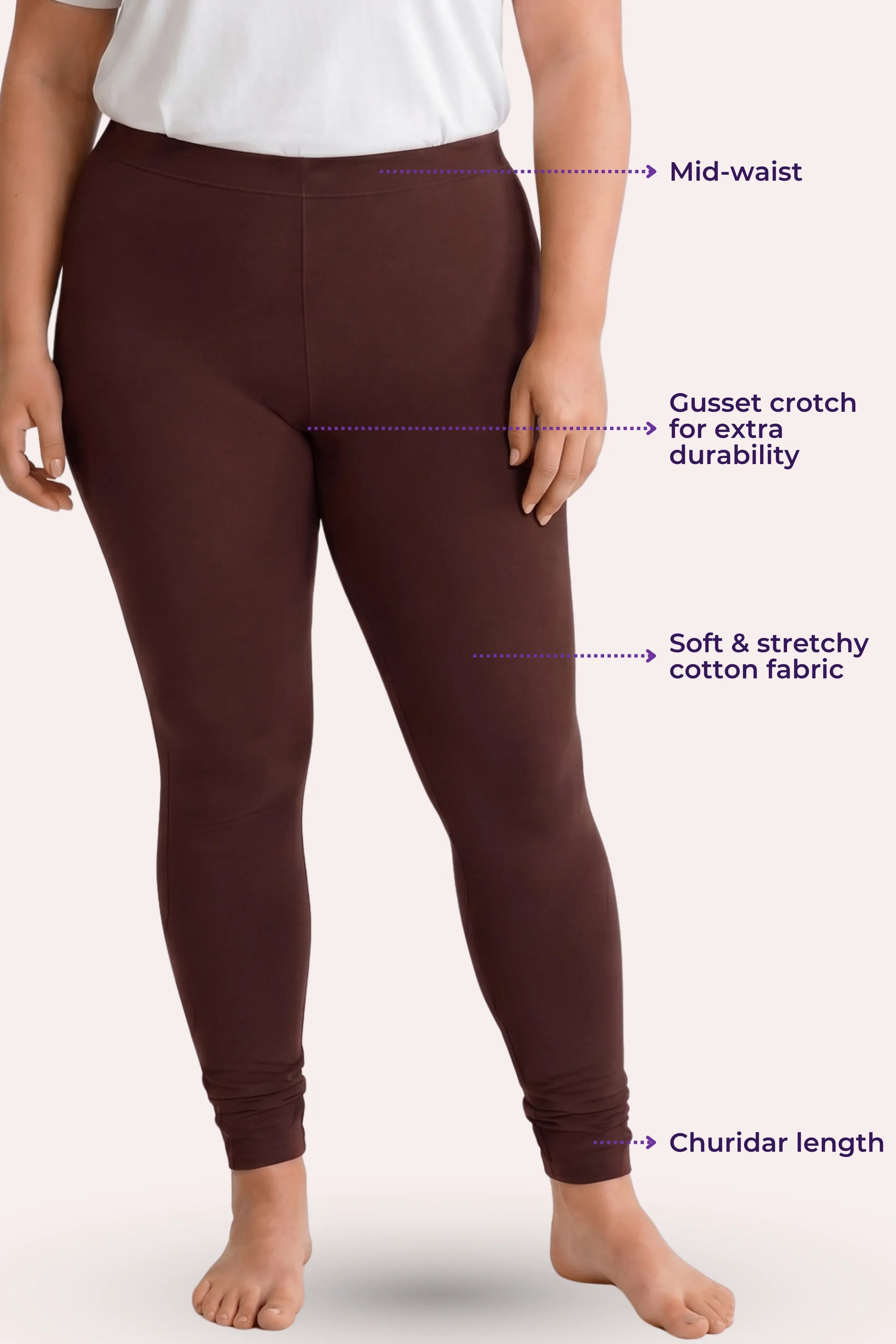 A model wearing brown leggings with text callouts pointing to the mid-waist, gusset crotch, stretchy fabric, and churidar length.