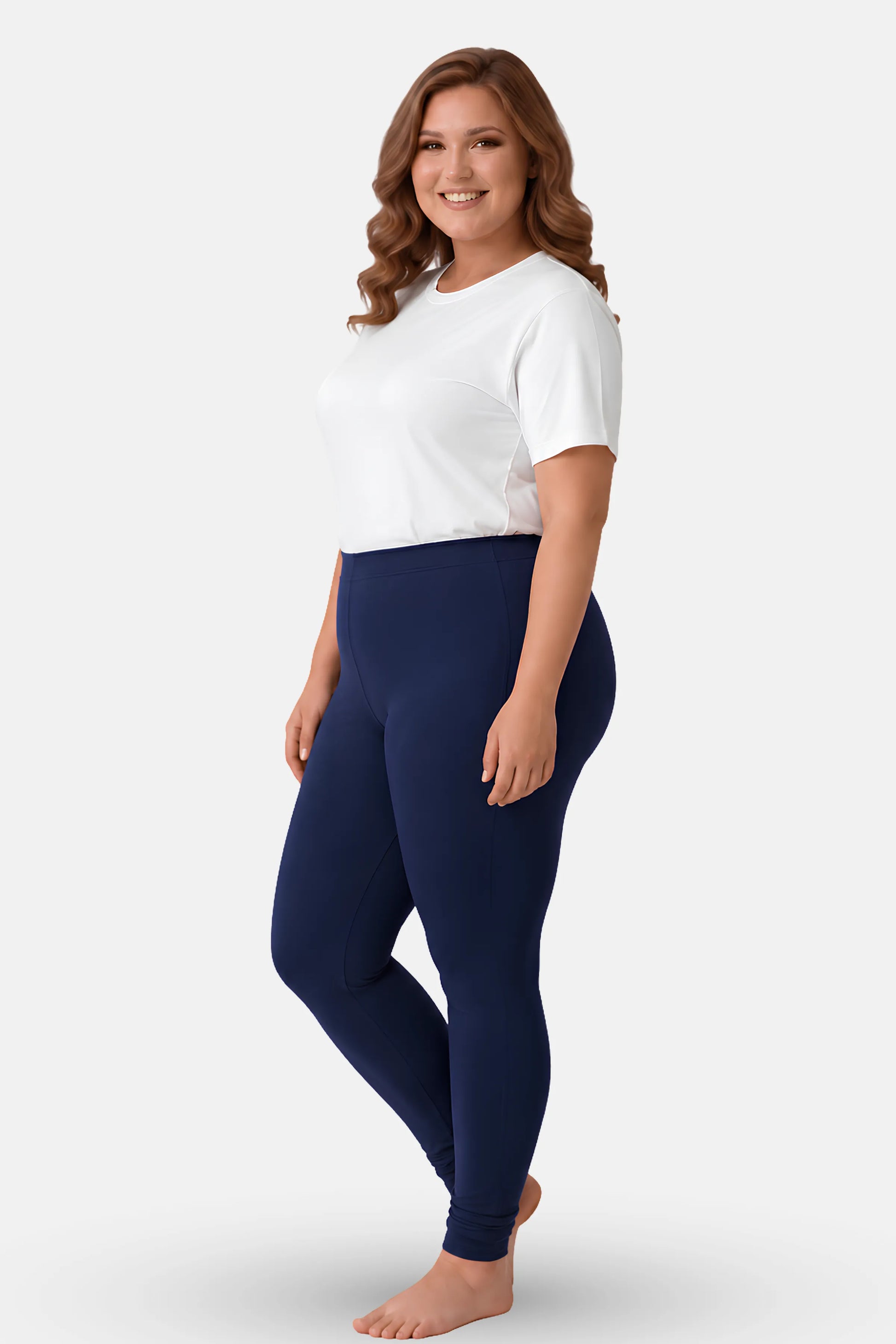 A woman modeling a white t-shirt and navy blue high-waisted leggings against a light gray studio background.