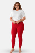 A woman modeling red churidar leggings with a white t-shirt, standing against a light gray studio background.