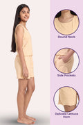 A girl modeling a light peachy-beige sleeveless romper with side pockets, shown in profile on the left, with three circular detail callouts on the right highlighting the round neckline, side pockets.
