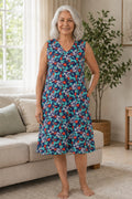 A elder woman wearing a sleeveless V-neck dress with a blue floral print.