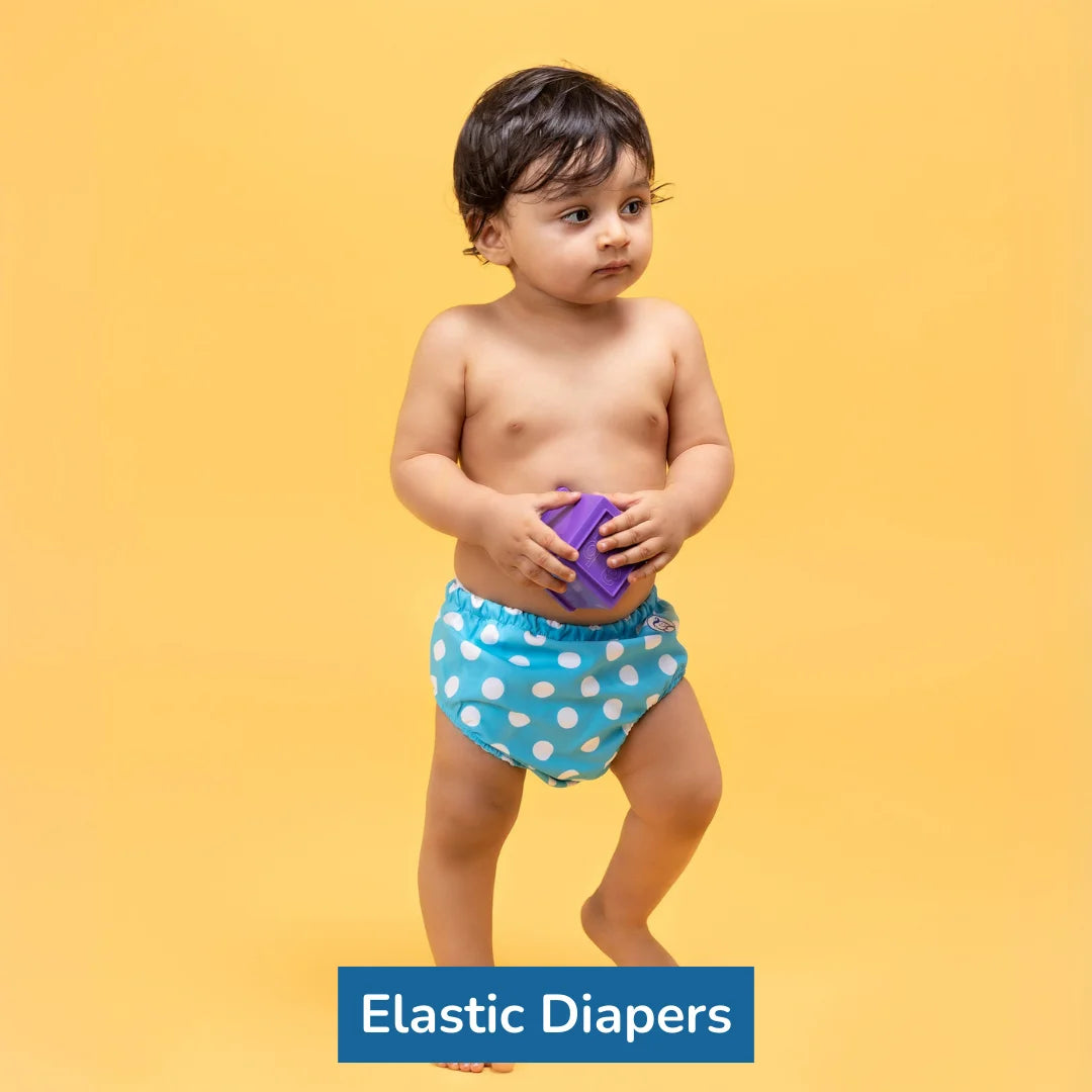 Image of a baby boy holding toy while wearing light blue color diaper with medium large while circles on it.