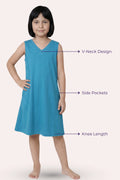 A girl model wearing a sleeveless peacock blue dress with a V-neck, side pockets, and knee-length.
