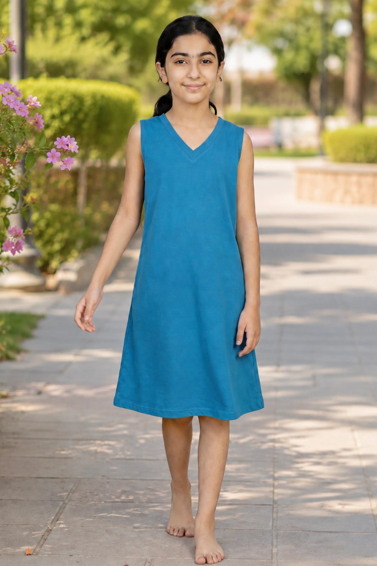 A young girl wearing a sleeveless blue V-neck dress