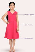 A young girl modeling a sleeveless bright pink dress with a V-neck, side pockets, and knee-length.