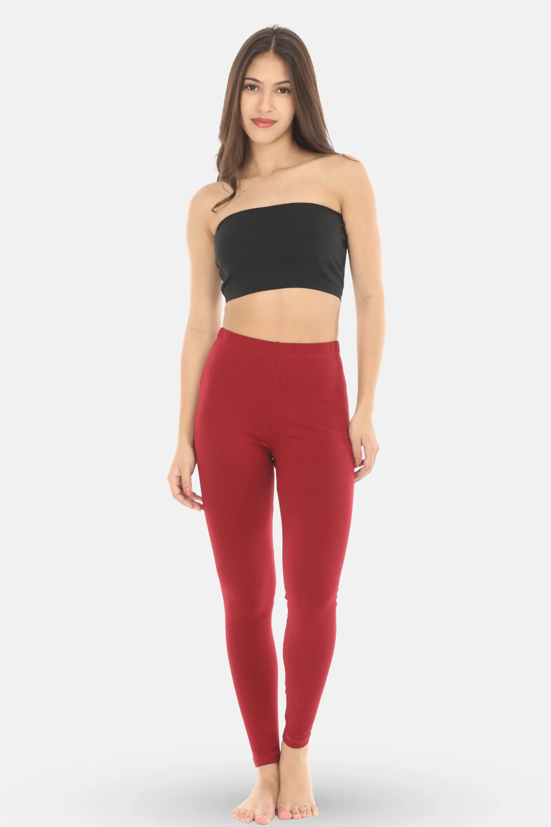 Woman wearing a black strapless top and maroon leggings on a white background