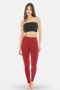 Woman wearing a black strapless top and maroon leggings on a white background