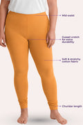 A model wearing caramel leggings with text callouts pointing to the mid-waist, gusset crotch, stretchy fabric, and churidar length.