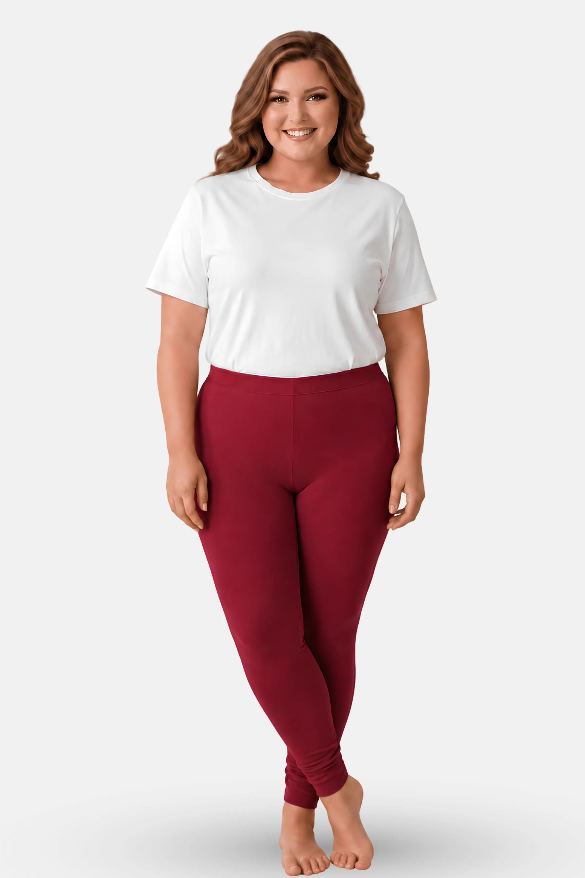 A woman modeling a white short t-shirt and maroon high-waisted leggings against a light gray studio background.