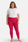 A woman modeling dark pink leggings with a white t-shirt, standing against a light gray studio background.