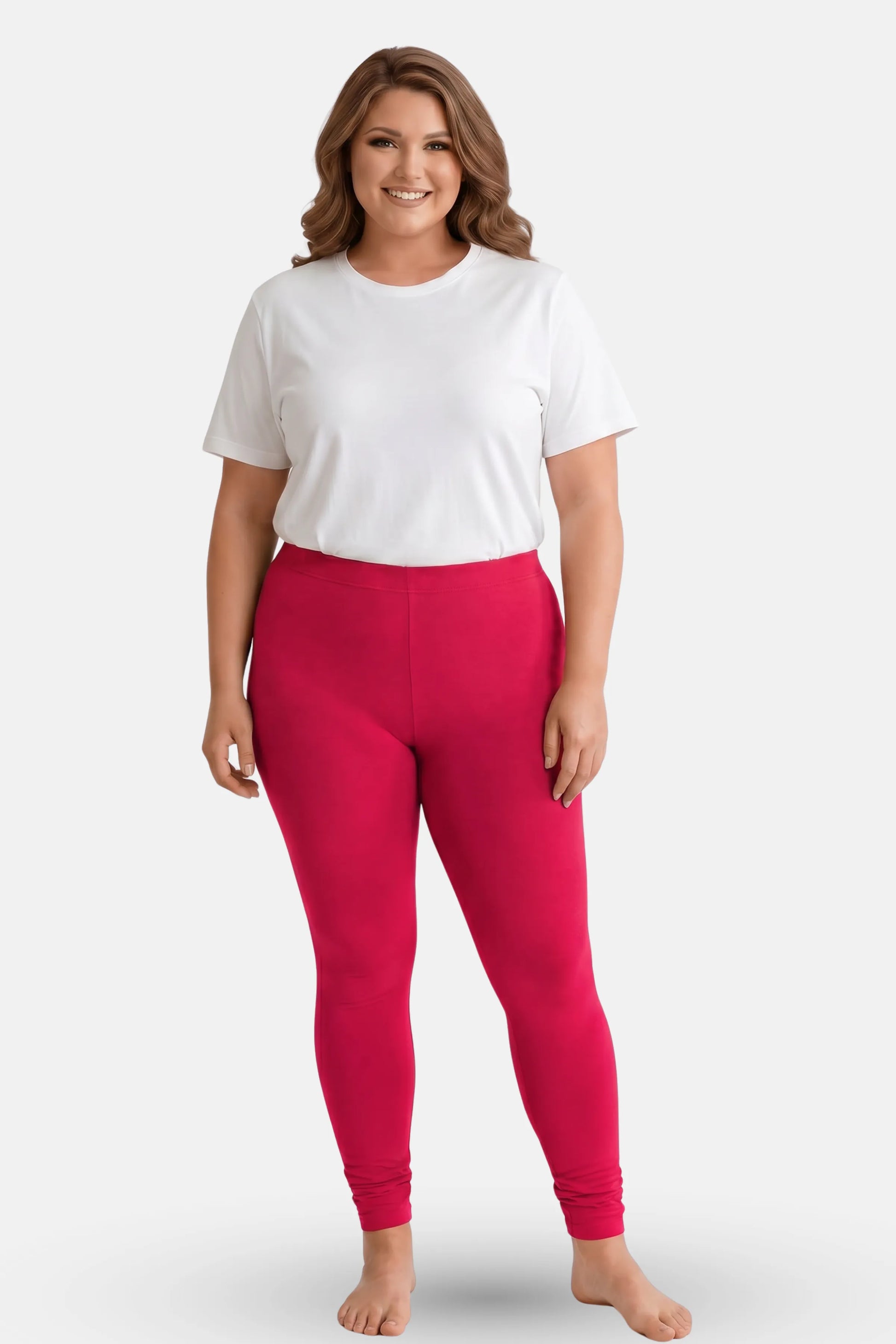 A woman modeling dark pink leggings with a white t-shirt, standing against a light gray studio background.