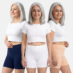 Woman wearing a three different poses with white crop top and navy blue, white & skin shorts on a white background