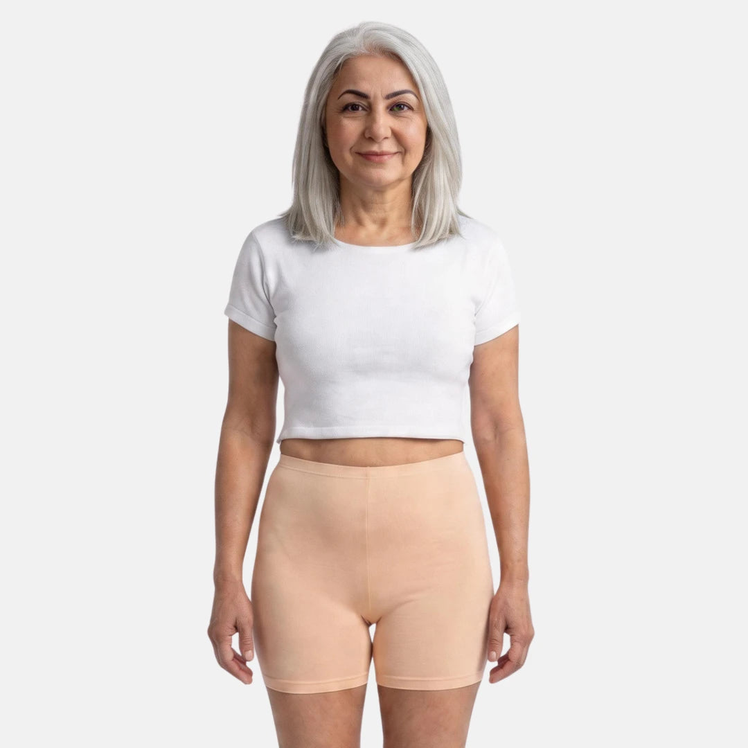 Woman wearing a white crop top and grey shorts on a white background