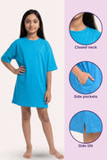 A girl model wearing a bright blue nightshirt. The callouts label features: a closed neck, side pockets, and a side slit.