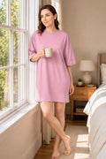 A woman wearing a oversized light pink short-sleeve nightshirt