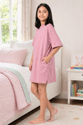 A girl wearing a pink dress with side pockets.