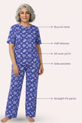 Woman wearing a navy hearts pajama set with heart and star pattern, labeled with features like round neck, half sleeves, all-over print, side pockets, and straight-fit pants