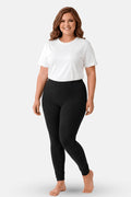 A woman modeling a white short t-shirt and black high-waisted leggings against a light gray studio background.