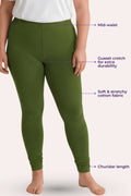 A women wearing green leggings against a pale pink background, with overlaid callout text pointing to the mid-waist, gusset crotch, stretchy fabric, and churidar length.