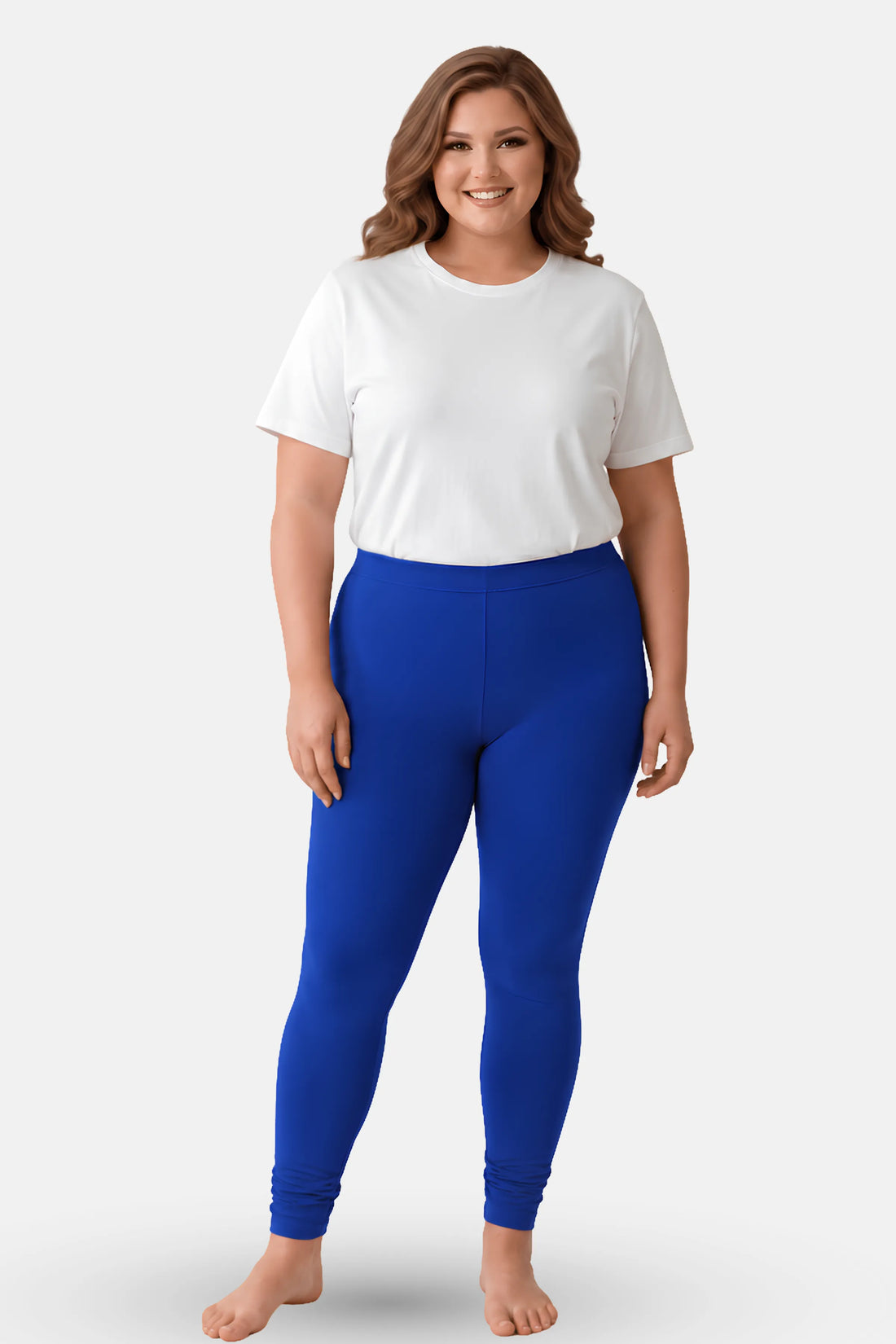 A woman modeling high-waisted, royal blue churidar leggings with a white t-shirt, standing against a light gray studio background.