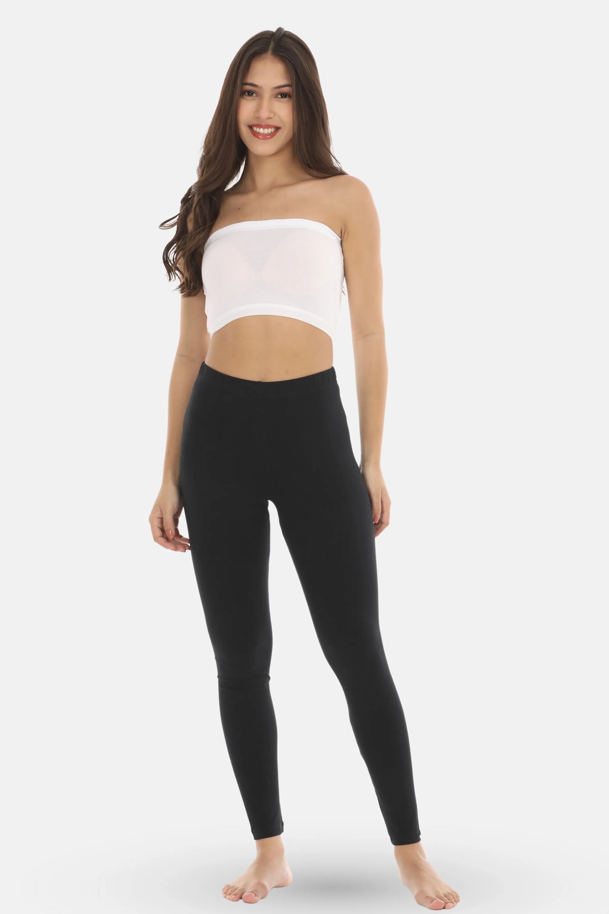 Woman wearing a white strapless top and black leggings on a white background